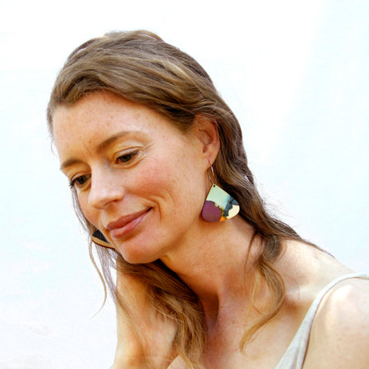 Model shot of wooden earrings named ‘droplet glow’ shaped as a natural drop. Made from sustainable wood with stainless steel hoops. Made in Australia.