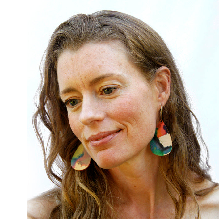 Model shot wearing wooden earrings named 'drop play' shaped as a rain drop. Made from sustainable wood with stainless steel hoops. Made in Australia.