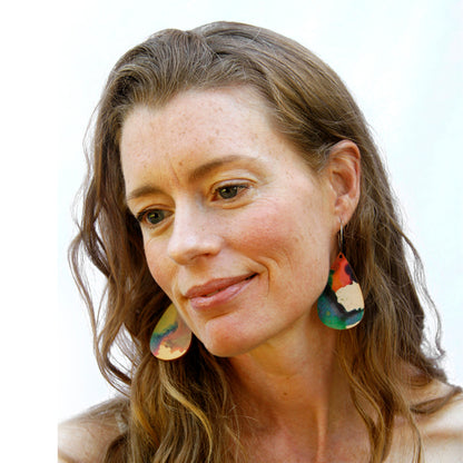 Model shot wearing wooden earrings named 'drop play' shaped as a rain drop. Made from sustainable wood with stainless steel hoops. Made in Australia.