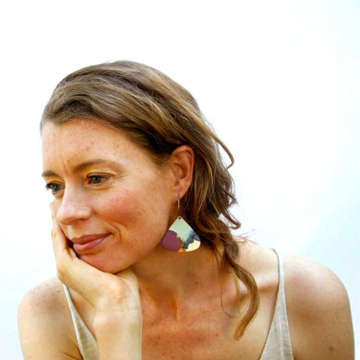 Model shot of wooden earrings named 'drop dive' shaped as a natural drop. Made from sustainable wood with stainless steel hoops. Made in Australia.