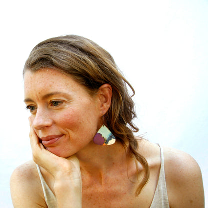 Model shot of wooden earrings named ‘droplet immersion’ shaped as a natural drop. Made from sustainable wood with stainless steel hoops. Made in Australia.