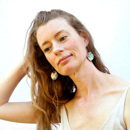 Model shot of wooden earrings named ‘Rock Drop Light’ shaped as a natural rock. Made from sustainable wood with stainless steel hoops. Made in Australia.