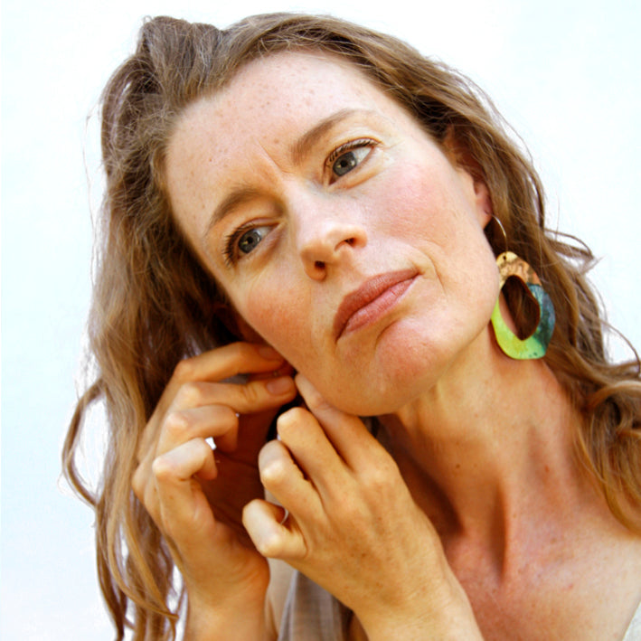 Model shot of wooden earrings named ‘Rock Hollow Ground’ shaped as a natural rock. Made from sustainable wood with stainless steel hoops. Made in Australia.