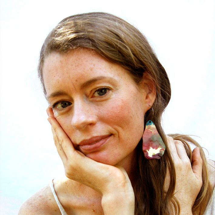 Model shot of wooden earrings named ‘Rock Flame shaped as a natural rock. Made from sustainable wood with stainless steel hoops. Made in Australia.