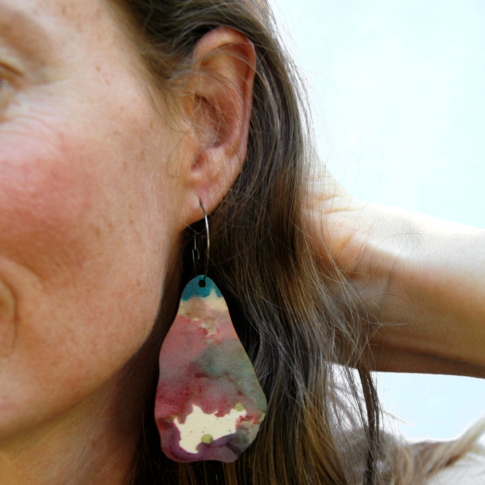 Model shot of wooden earrings named ‘Rock Land’ shaped as a natural rock. Made from sustainable wood with stainless steel hoops. Made in Australia.