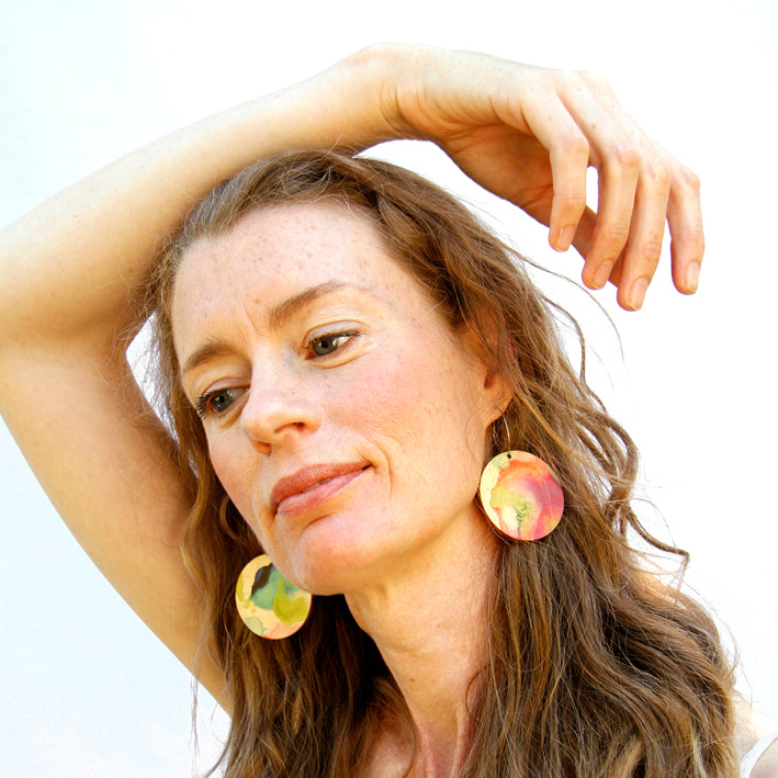 Model shot of wooden earrings named ‘Round 45 Sky’ with a round shape. Made from sustainable wood with stainless steel hoops. Made in Australia.